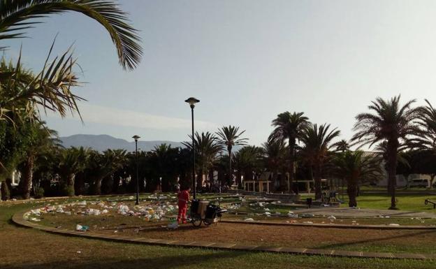 Un operario recoge restos del botellón de la noche anterior en Balerma.