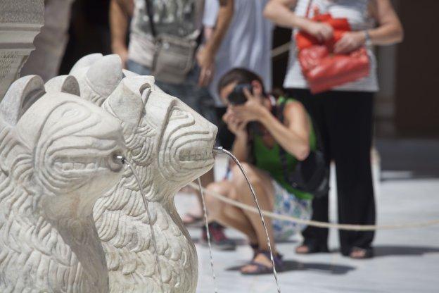 Una mujer fotografía uno de los leones del famoso patio.