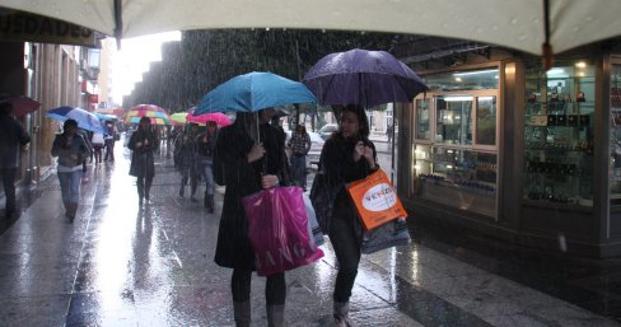 Dos chicas caminan bajo la lluvia por el Paseo de Almería.