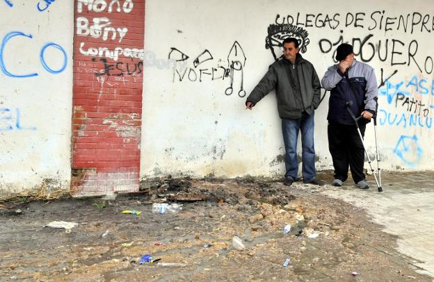 Unos vecinos muestran la arqueta por la que salen basura y malos olores a la calle Blasco Ibáñez./ENRIQUE