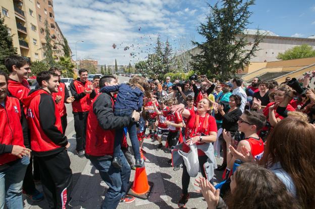 Los aficionados recibieron con júbilo a los jugadores del Covirán a su llegada ayer a Granada, arriba Eloy Almazán aúpa a una niña y a la izquierda, Carlinhos baja del autobús. /Alfredo Aguilar