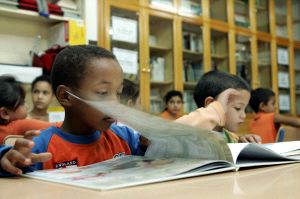 LENGUAJE. Unos niños miran un libro en una biblioteca escolar, donde se familiarizan con el español. / IDEAL/