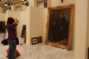 Una fotógrafa capta la imagen de un cuadro y, a la derecha, varias obras a la espera de ser instaladas en los paneles. :: M. MANZANO/